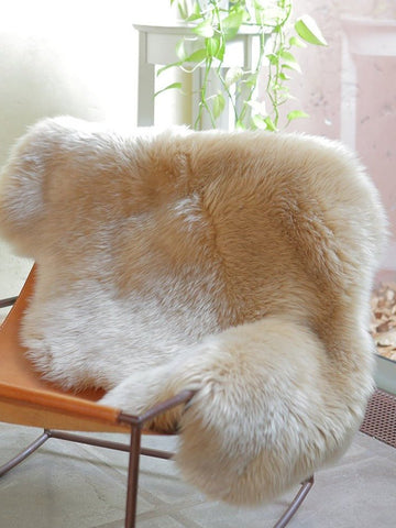 Single Patagonian Fur Rug draped over a saddle leather chair in a cozy, minimalist room.